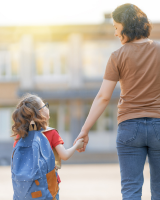 Une maman tient la main à son fils pour l'amener à l'école