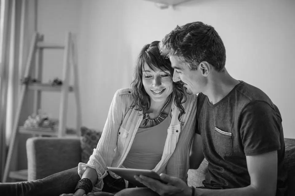 Couple qui regarde en souriant son ordinateur