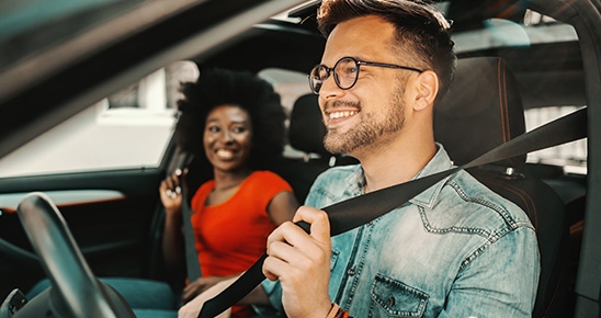 Homme et femme souriant au volant d'une voiture