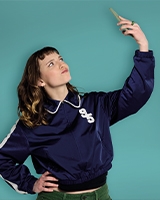 une jeune fille se prend en selfie devant un fond bleu