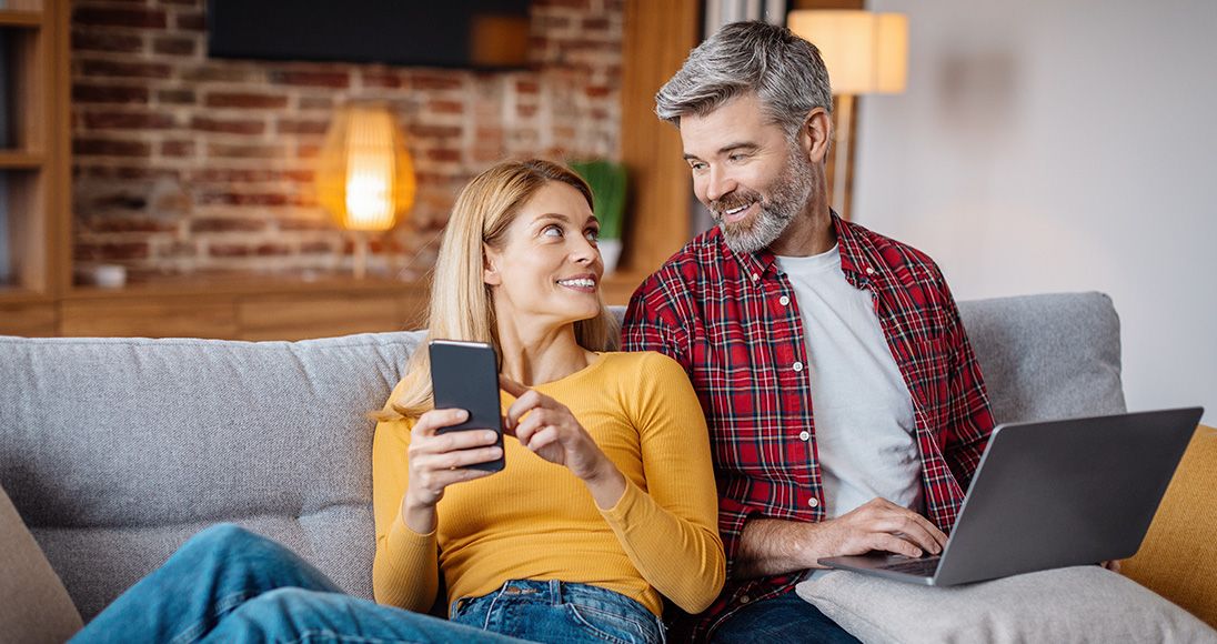 Un couple souriant qui regarde un ordinateur portable