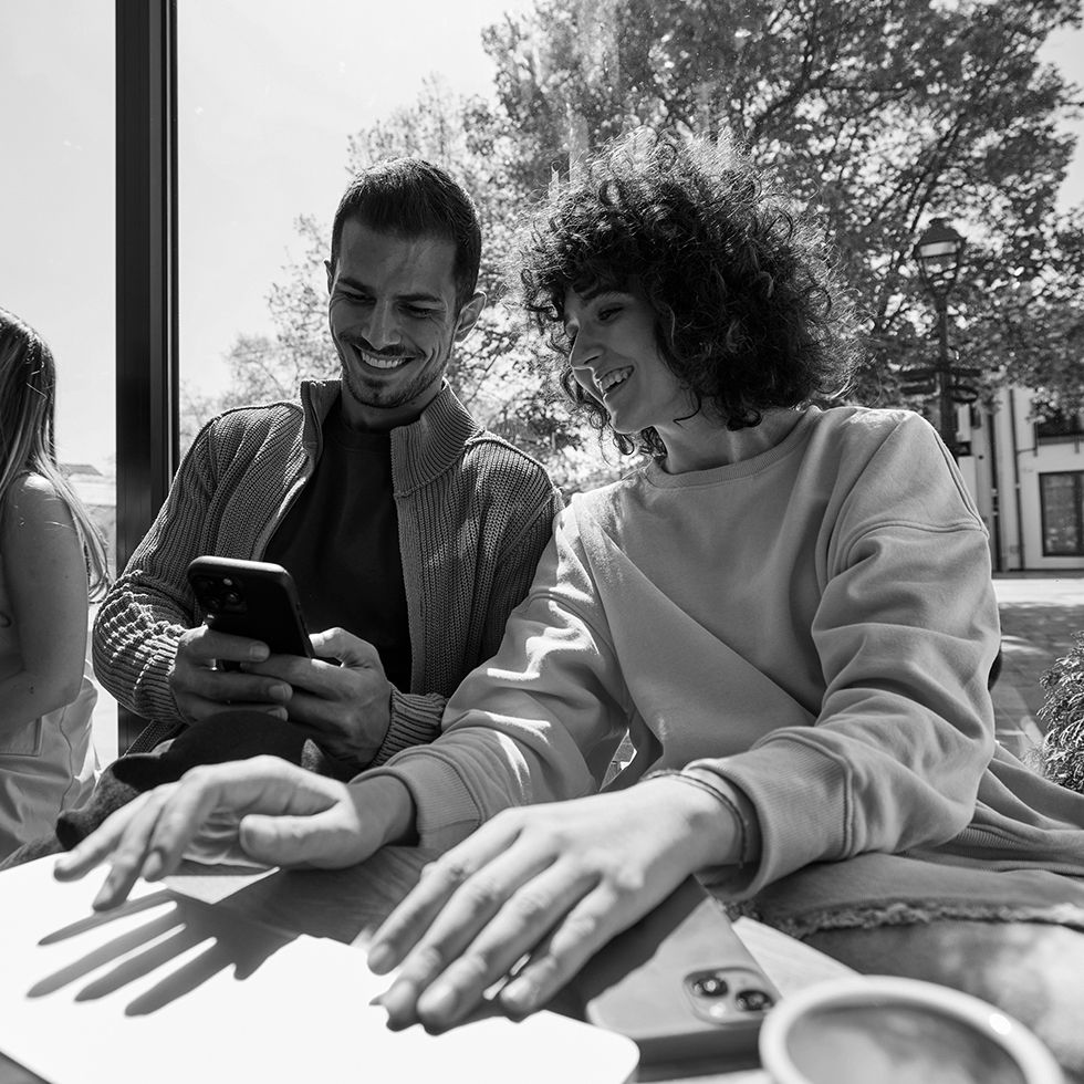 Un jeune homme et une jeune femme discutent de leurs investissement à la terrasse d'un café