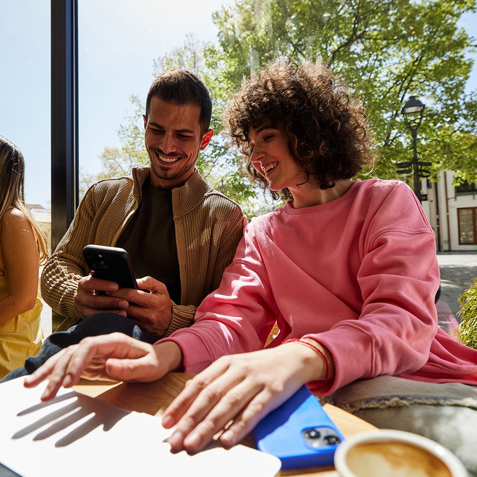 Un jeune homme et une jeune femme discutent de leurs investissement à la terrasse d'un café