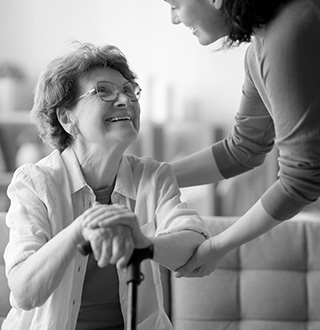 Personne âgée avec une canne qui se fait aider par une jeune femme