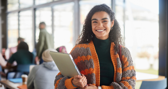 Etudiante souriante tenant un cahier dans une bibliothèque lumineuse