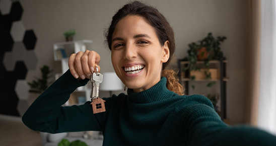 Femme souriante se prenant en photo tenant des clés d'appartement